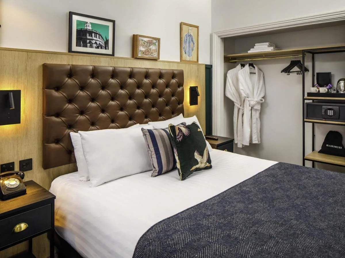 a bedroom with a large bed with a large headboard at Mercure Oxford Hawkwell House Hotel in Oxford