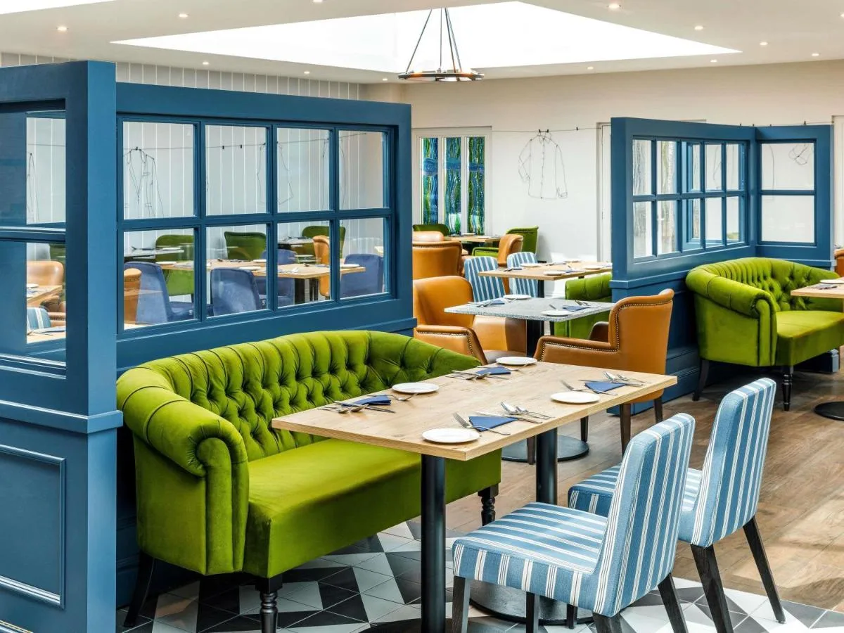 a restaurant with green furniture and tables and chairs at Mercure Oxford Hawkwell House Hotel in Oxford